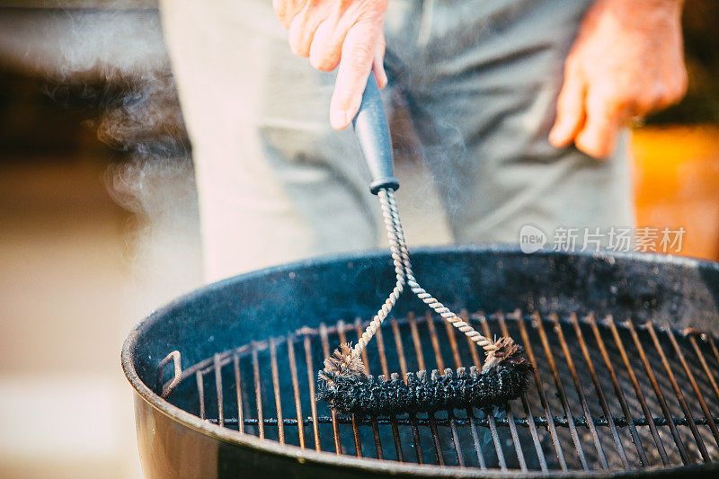 Man using brush to clean barbecue grill